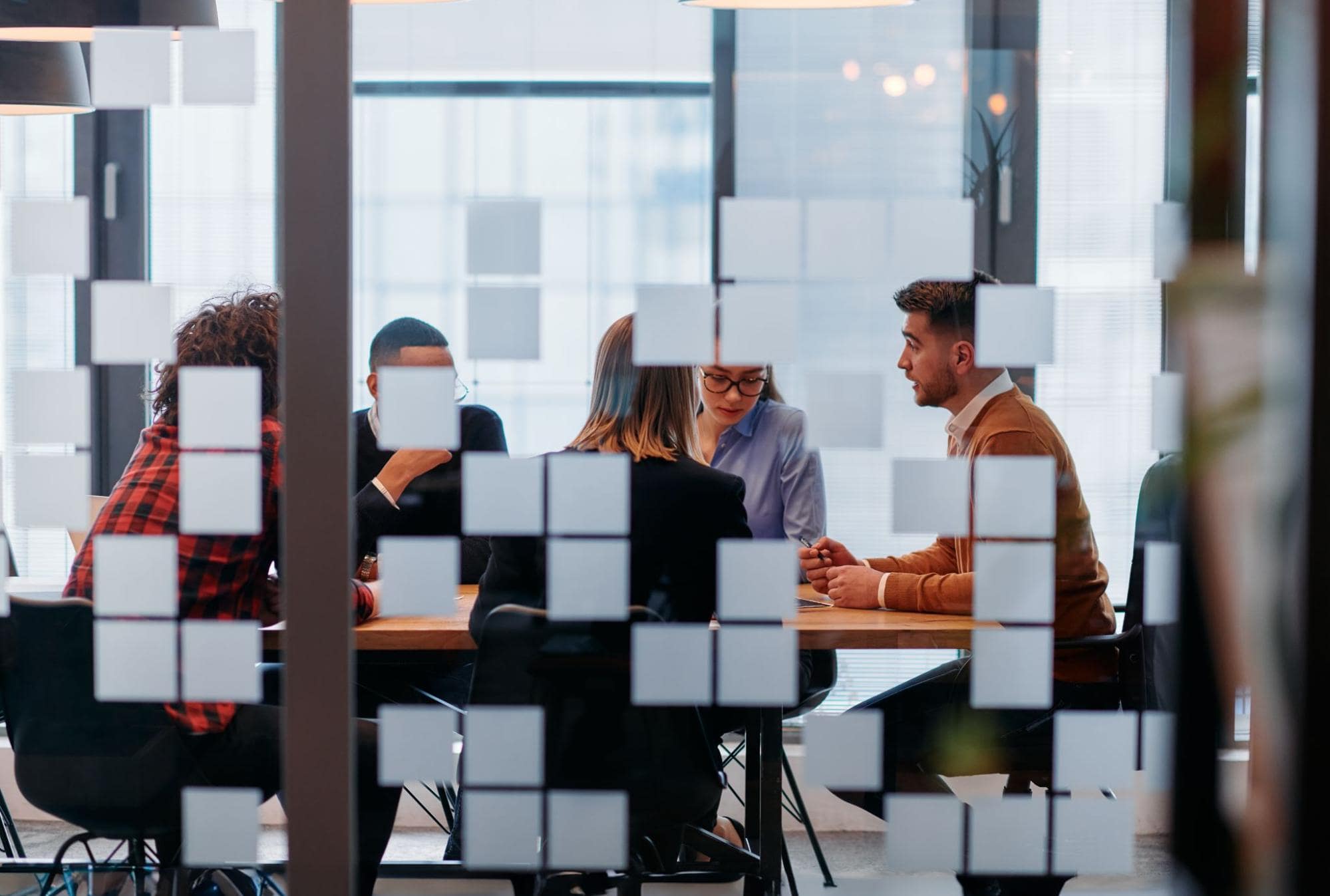 View of conference room meeting through pane of glass where employees are celebrating fastest growing staffing firms award