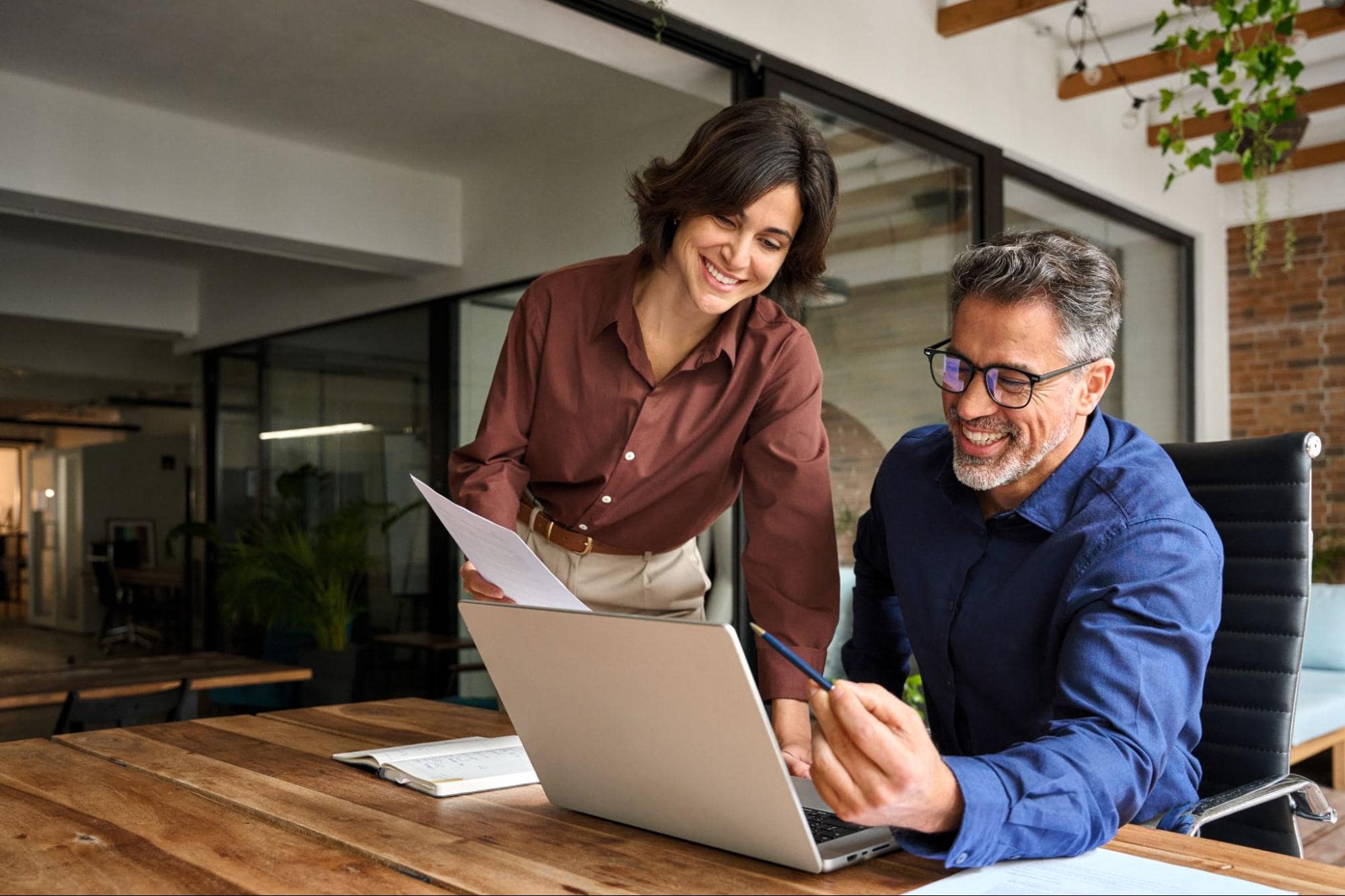 Male and Female Office Employees Working at Desk With Computer Reviewing Production Manager Skills and Qualifications