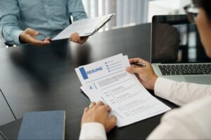 Recruiters at conference table discussing paper resume and reviewing the top manufacturing resume tips