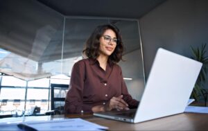 A focused professional woman working on a laptop, reviewing successful linkedin profile examples to refine her own executive summary and career pitch.