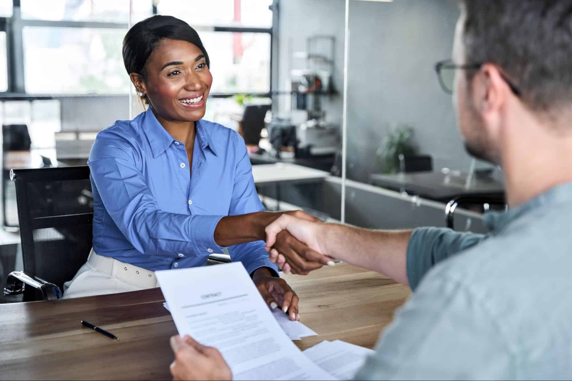 A professional recruitment consultant shaking hands with a candidate in a modern office, representing successful tips on selecting construction headhunters to ensure a high-quality hiring process.