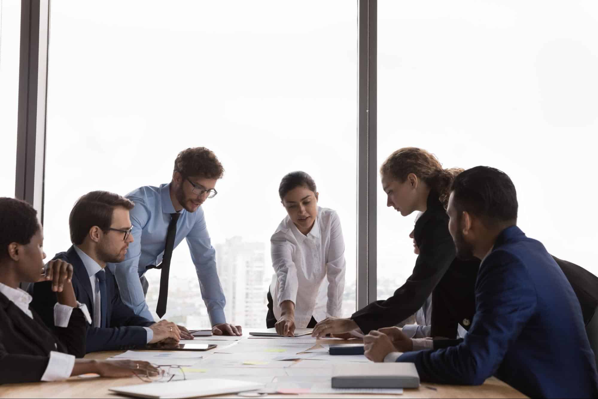 A diverse group of business leaders collaborating on documents for effective succession planning in a bright office.