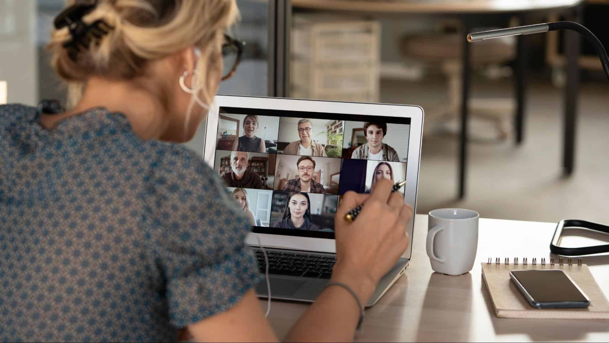 A professional woman participating in a multi-person video conference call from a home office, highlighting the efficiency of flexible work arrangements.