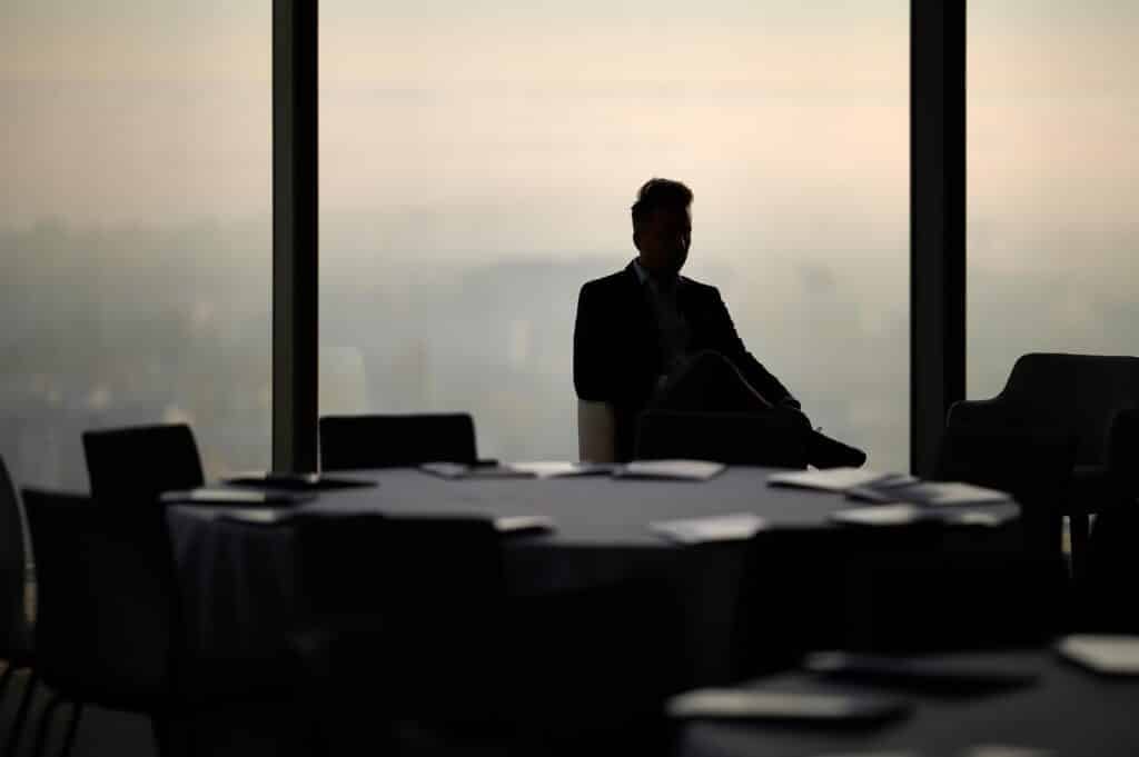 Silhouette of an executive seated in an empty high-rise boardroom overlooking a city skyline during a confidential executive search