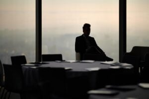 Silhouette of an executive seated in an empty high-rise boardroom overlooking a city skyline during a confidential executive search