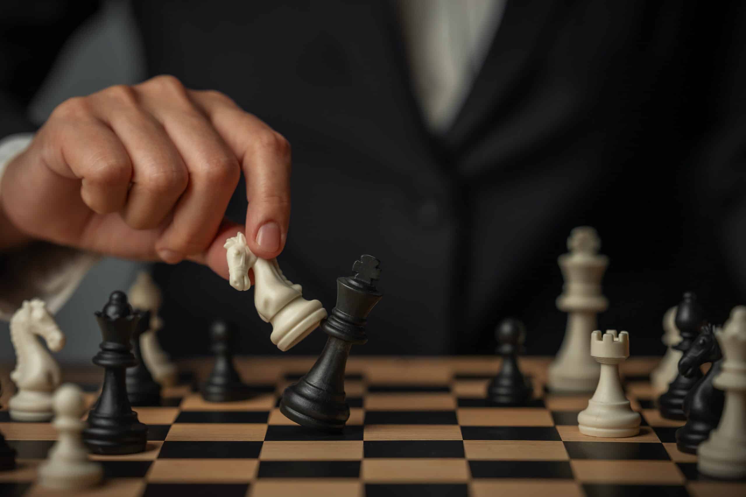 A person in a business suit making a strategic chess move, replacing a black piece with a white knight on a chessboard